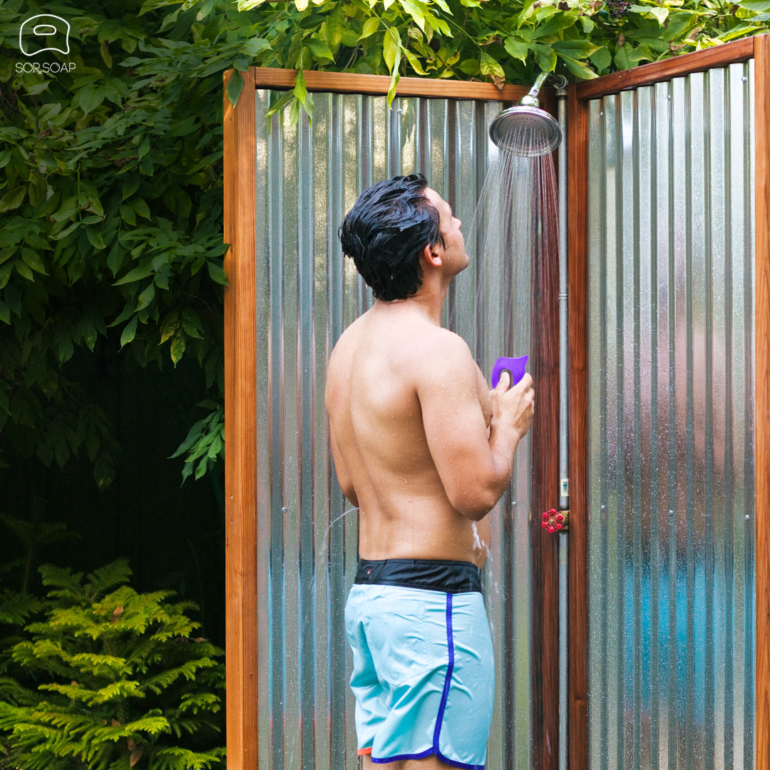 Refreshing outdoor shower scene featuring a man using the purple SORSOAP bar for a rejuvenating and natural cleansing experience.