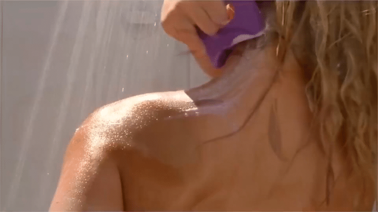 Sore Woman Scraping Stressed Shoulder with Sorsoap in Shower