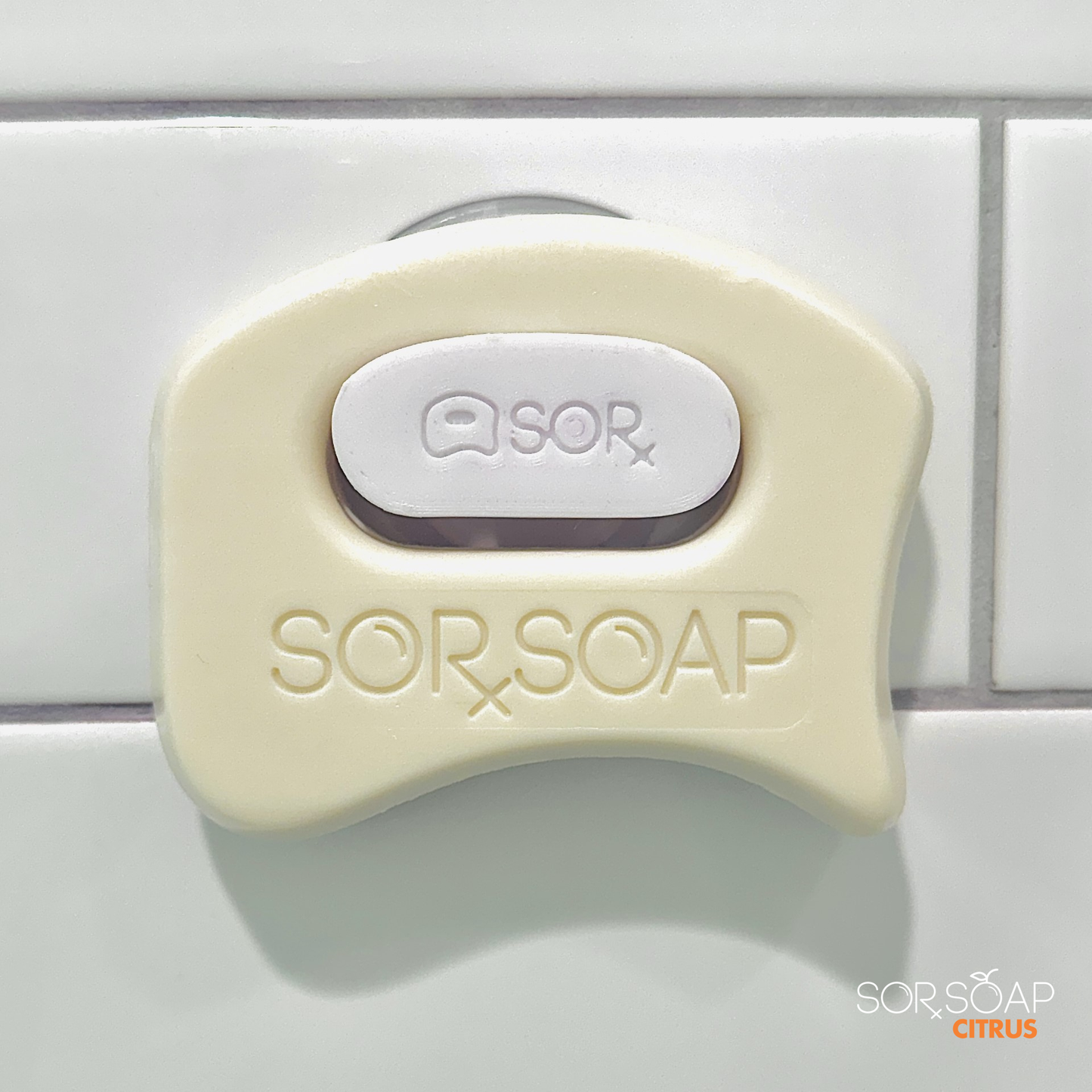 SORSOAP Citrus bar securely mounted with its suction cup holder, ideal for a clean and refreshing shower experience.